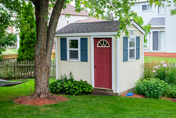 A cream shed with a red door in backyard